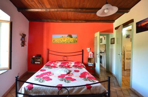 um quarto com uma parede vermelha e uma cama. em Il Girasole em Mazzano Romano