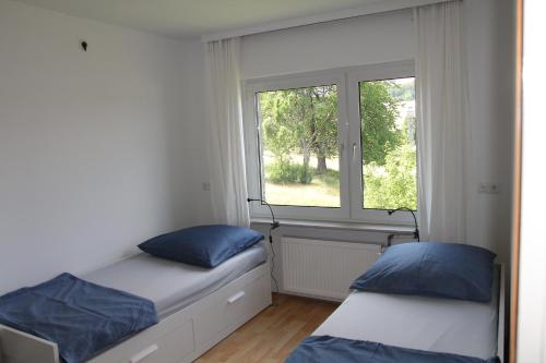 zwei Betten in einem Zimmer mit Fenster in der Unterkunft Bike and Hike Ferienhaus Kolverath in Kolverath