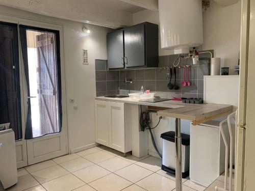 a kitchen with white cabinets and a table and a window at La Garde Studio centre historique, proche plage, climatisation, fibre in La Garde