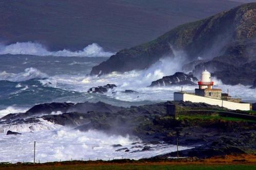 a lighthouse in the ocean with a large wave at Royal Valentia Hotel in Valentia Island