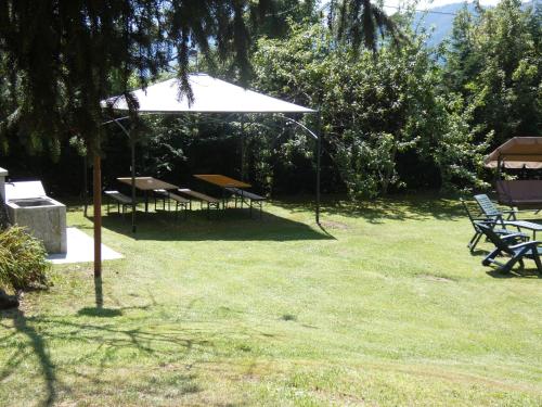 a group of picnic tables and an umbrella in the grass at Baita Figliezzi in Castello Tesino