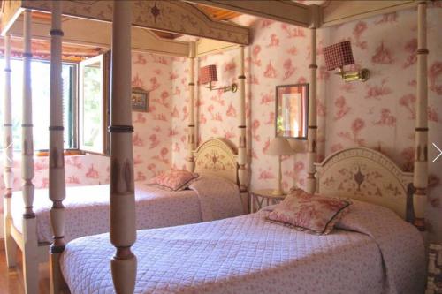 two beds in a bedroom with pink wallpaper at Family Dream in Colares
