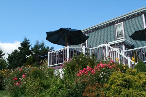 una casa con porche con sombrilla y flores en Surfside Inn, en Hubbards