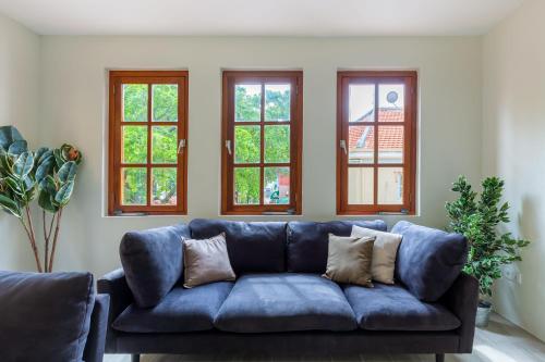 a blue couch in a living room with windows at Boutique Homes Willemstad City Centre in Willemstad