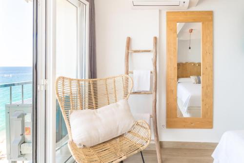 a wicker chair in a room with a mirror at Sugar Beach Boutique Studio in Platja d'Aro