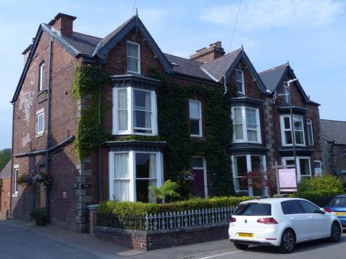 a white car parked in front of a brick house at Four Seasons Guesthouse in Castleton