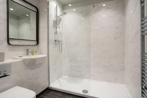 a white bathroom with a shower and a sink at Hillyard House Hotel in Castlewellan