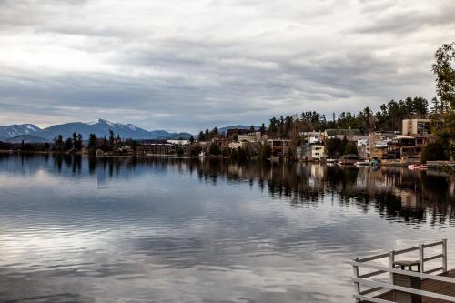 a view of a lake with buildings and mountains at The Haus On Mirror Lake in Lake Placid