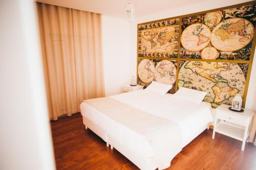 フィゲイラ・ダ・フォズにあるPuzzle Suites B&Bの白いベッドと地図付きの壁が備わるベッドルーム1室が備わります。