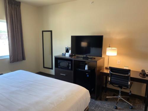 a hotel room with a bed and a desk and a television at Cobblestone Inn & Suites - Forest City in Forest City