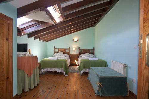 a bedroom with two green beds and wooden floors at Posada los Taranos in Valdaliga 