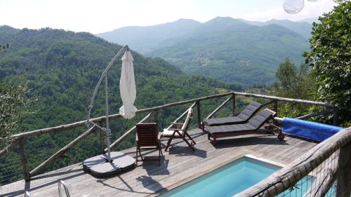 a deck with chairs and an umbrella and a swimming pool at piscina con vista in Bagni di Lucca