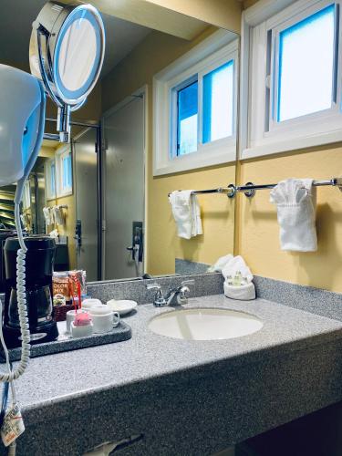 a bathroom counter with a sink and a mirror at Monterey Bay Lodge in Monterey