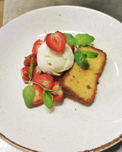 a white plate with a dessert with strawberries and ice cream at Örserumsbrunn Gestgifveri & Konferens in Gränna