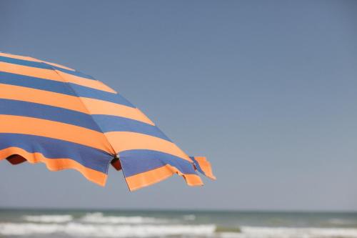 an orange and blue striped umbrella on the beach at Hotel Lido in Vasto