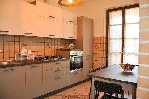 cocina con armarios blancos y mesa en Monolocale - B&B Sarita's Rooms, en Certosa di Pavia