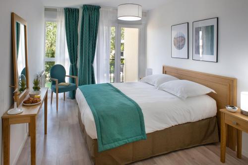 een slaapkamer met een groot bed en een groene deken bij Domitys - L'Atlas in Arras