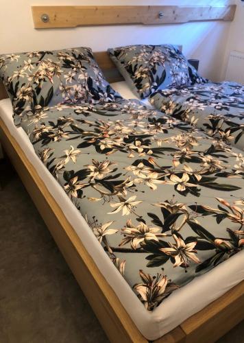 a bed with a black and white bedspread with flowers on it at Kameňácká myslivna in Moravany