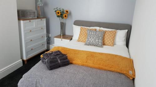 Townhouse @ Birches Head Road Stoke في ستوك أون ترينت: سرير مع بطانية برتقال و مزهرية من الزهور
