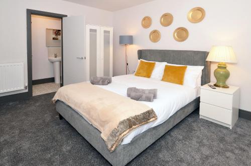 um quarto com uma grande cama branca com almofadas laranja em Townhouse PLUS @ London Road Stoke em Stoke-on-Trent