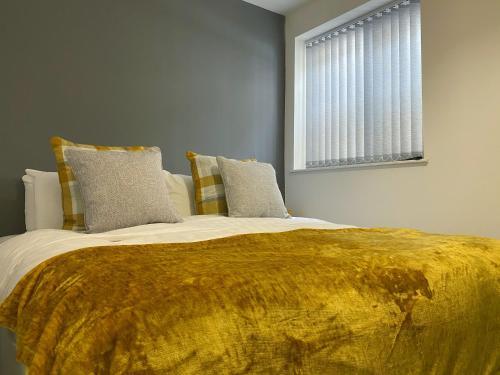 a bedroom with a large bed with a yellow blanket at Kensington Suite Sasco Apartments in Blackpool