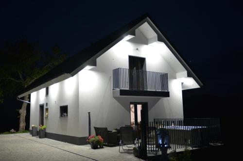 a white house with a balcony at night at Tanja s Holiday Home in Nature with sauna and hot tub in Gorica pri Slivnici