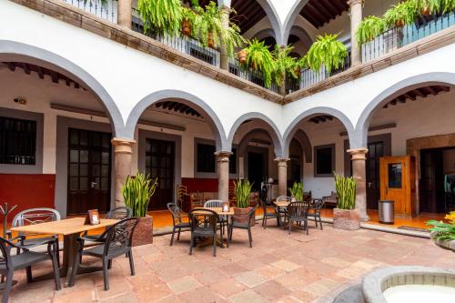 an outdoor patio with tables and chairs in a building at Hotel Hidalgo in Querétaro