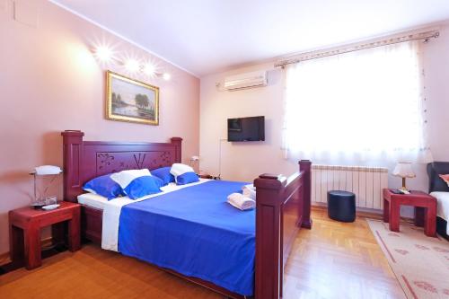 una camera da letto con un letto con lenzuola blu e una TV di Villa Tower Gardos a Belgrado