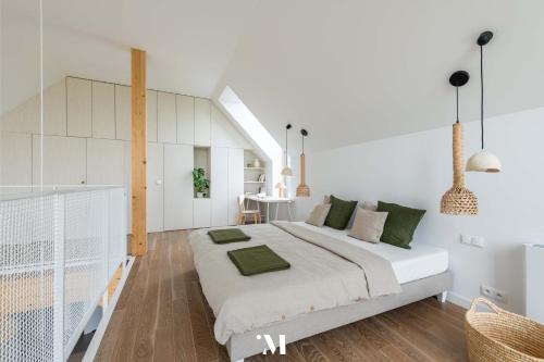 a white bedroom with a large bed with green pillows at Punkt Mazury in Sędki