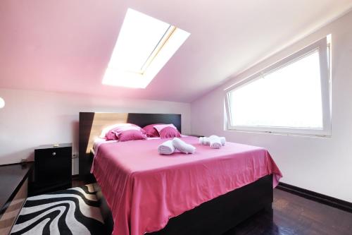 a bedroom with a pink bed with two towels on it at Villa Tower Gardos in Belgrade