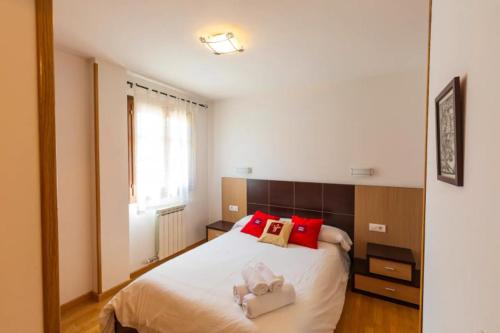 a bedroom with a white bed with red pillows at Pirineos360 - Partacua - Centro de Panticosa con garaje y trastero in Panticosa