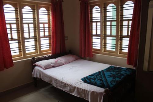 uma pequena cama num quarto com janelas em Comfort Zone Homestay em Madikeri