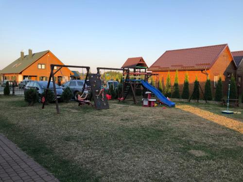 a park with a playground with a swing set and cars at Anida Rusinowo in Rusinowo