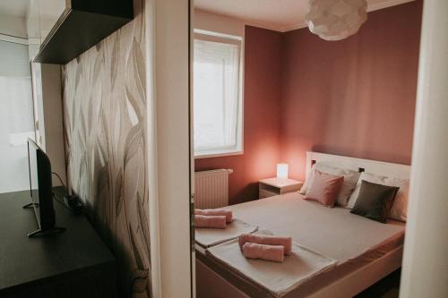 a small bedroom with a bed with pink walls at Apartment Nika, Arena Zagreb in Zagreb