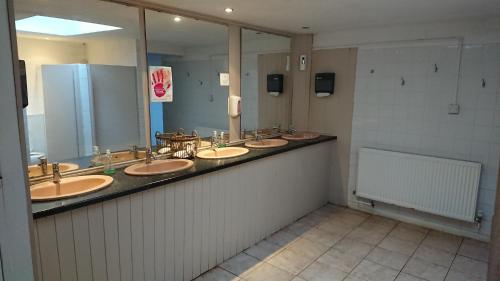 La salle de bains est pourvue de 4 lavabos et d'un grand miroir. dans l'établissement X Adventure, à Horsford