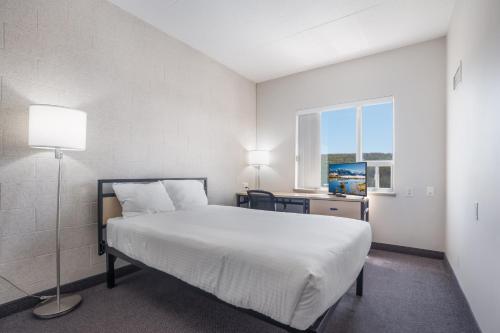 a bedroom with a white bed and a window at Residence & Conference Centre - Niagara-on-the-Lake in Niagara on the Lake