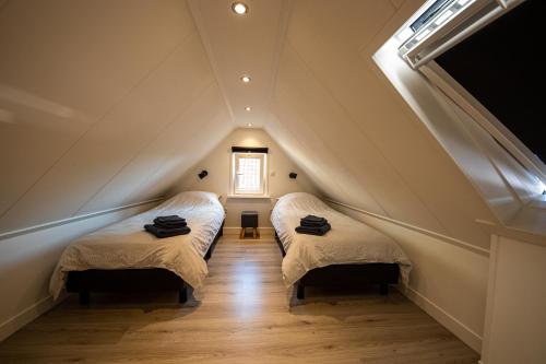 2 Betten in einem Dachzimmer mit Fenster in der Unterkunft BeachWay in Nes