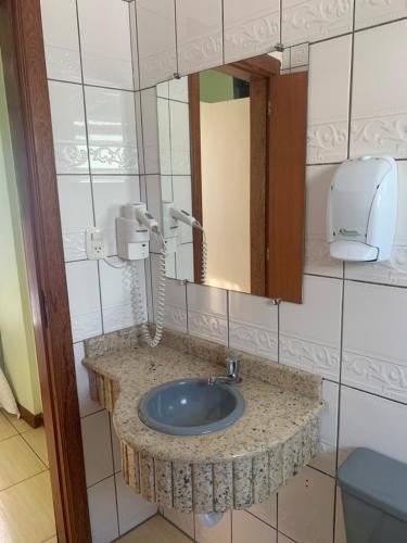 a bathroom with a sink and a mirror at Hoteis Cattoni Executive in Lages