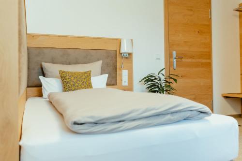 a bed with white sheets and pillows on it at Kondrauer Hof in Waldsassen