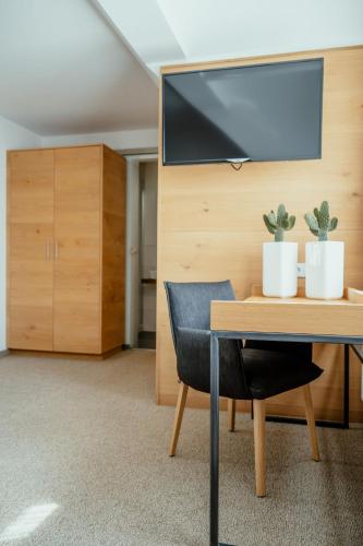 a table with a chair and a tv on a wall at Kondrauer Hof in Waldsassen