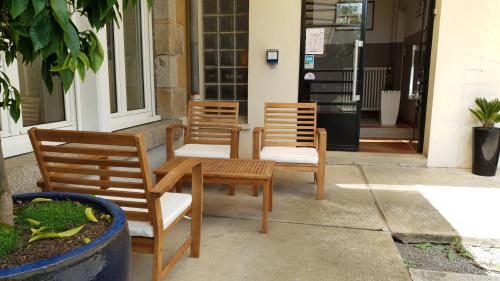 three chairs and a table in front of a building at Cosy Er Lann Gîte Cèdre in Val Couesnon