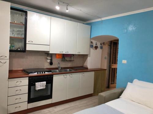 eine Küche mit weißen Schränken, einem Waschbecken und einem Bett in der Unterkunft Cottage Azzurra in Ischitella