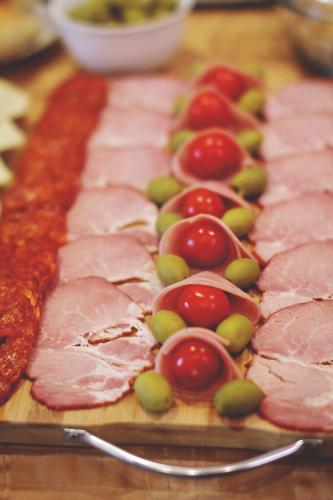 a wooden cutting board with ham and cherries on it at B&B Vila Tamaris in Zaječar