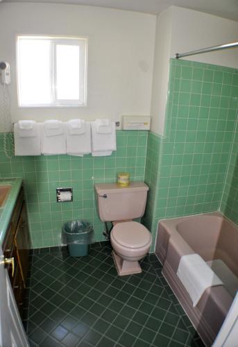a green tiled bathroom with a toilet and a tub at Uptown Inn in Port Angeles