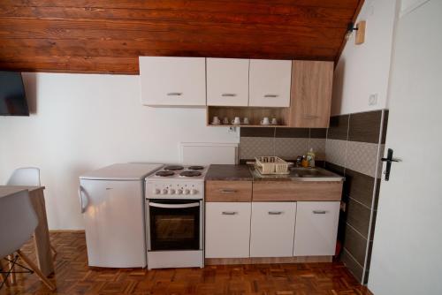 a kitchen with white cabinets and a stove top oven at Apartmani Sunčev breg Vlasinsko jezero in Surdulica