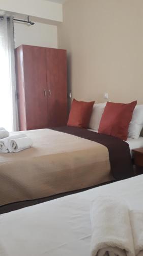 a bedroom with two beds with red pillows at Evdokia's Apartments and Rooms in Neos Marmaras
