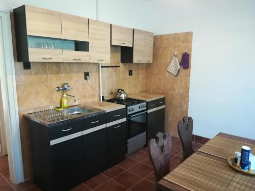 una cucina con armadi neri, lavandino e tavolo di Sétány Apartmanház Fonyód a Fonyód