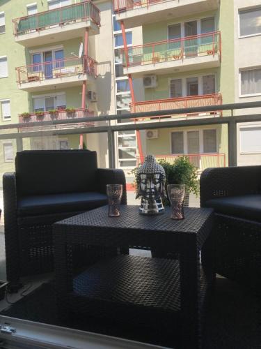 a black table on a balcony with chairs and a building at Swiss Luxury Apartment in Mosonmagyaróvár