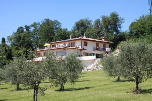 ein Haus auf einem Hügel mit Bäumen im Vordergrund in der Unterkunft Agriturismo Nonna Bettina in Moniga