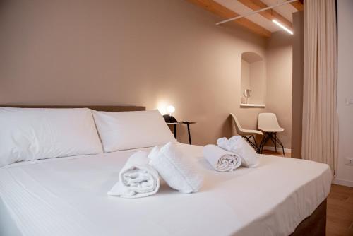 Un dormitorio con una cama blanca con toallas. en Tergestroom & boutique apartments, en Trieste